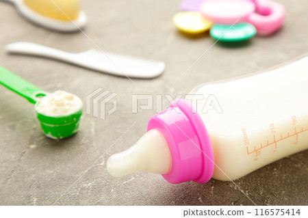 Baby milk with toys on grey background Baby milk with toys on grey background 116575414