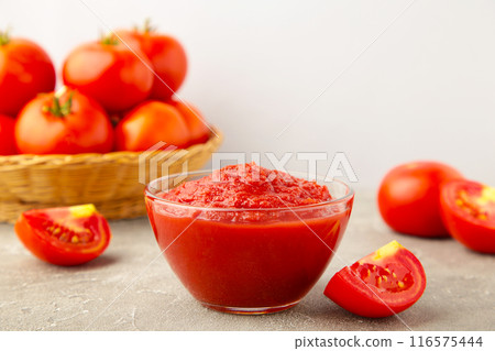 Tomato ketchup sauce in a bowl with tomatoes on grey wooden background. View from above. 116575444