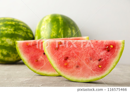 Fresh ripe striped sliced watermelon on grey background. Fresh ripe striped sliced watermelon on grey background. 116575466
