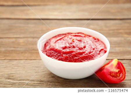 Tomato ketchup sauce in a bowl with tomatoes on grey wooden background. View from above. 116575474