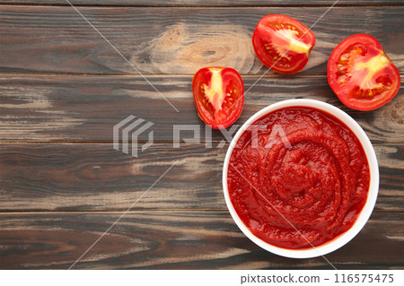 Tomato ketchup sauce in a bowl with tomatoes on brown. View from above. Tomato ketchup sauce in a bowl with tomatoes on brown. View from above. 116575475