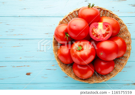 Ripe red tomatoes in basket on blue wooden background. 116575559
