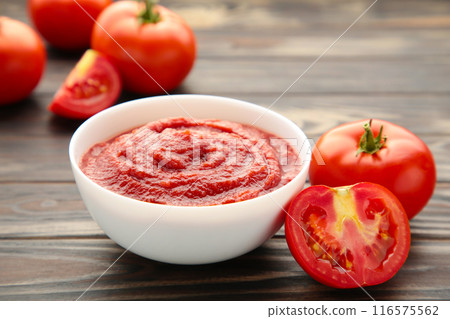 Tomato ketchup sauce in a bowl with tomatoes on brown. View from above. Tomato ketchup sauce in a bowl with tomatoes on brown. View from above. 116575562