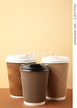 Three brown cups of coffee on beige background. Vertical foto 116575582