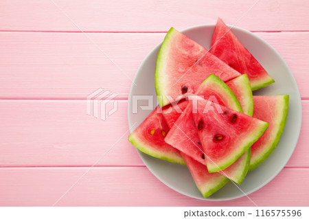 Fresh ripe striped sliced watermelon in the plate on pink wooden background. Fresh ripe striped sliced watermelon in the plate on pink wooden background. 116575596