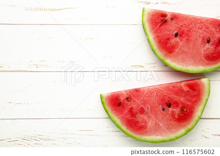 Fresh ripe striped sliced watermelon on white wooden background. 116575602