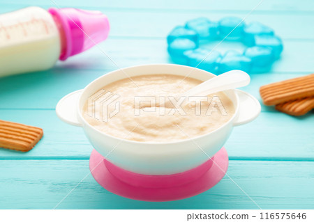 Bowl with baby food with toys on blue background Bowl with baby food with toys on blue background 116575646