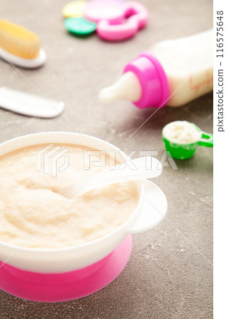 Milk and bowl with porridge for baby on grey background Milk and bowl with porridge for baby on grey background 116575648
