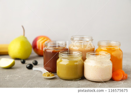 Glass jars with nutrient baby food on grey background Glass jars with nutrient baby food on grey background 116575675