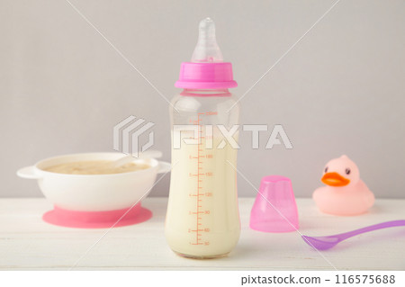 Bowl with baby food with toys on grey background 116575688
