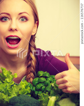 Woman in kitchen with green vegetables 116576737