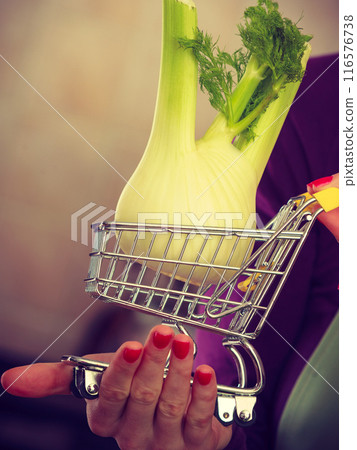 Woman holding shopping cart with fennel inside Woman holding shopping cart with fennel inside 116576738