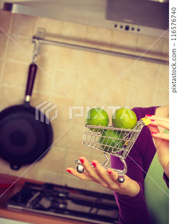 Woman holding shopping cart with limesinside 116576740