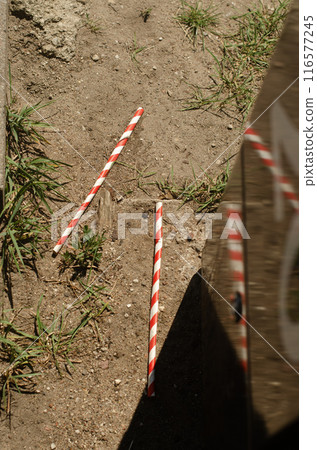 two red with white paper straws thrown out on the ground . High quality photo two red with white paper straws thrown out on the ground . High quality photo 116577245