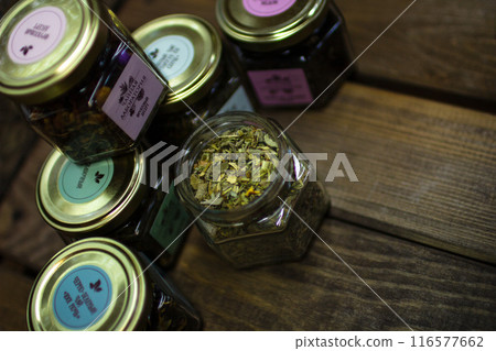 Small jars with various types of green fruit tea standing on a wooden table 116577662