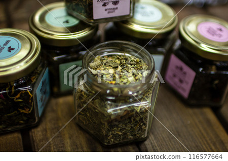 Small jars with various types of green fruit tea standing on a wooden table 116577664