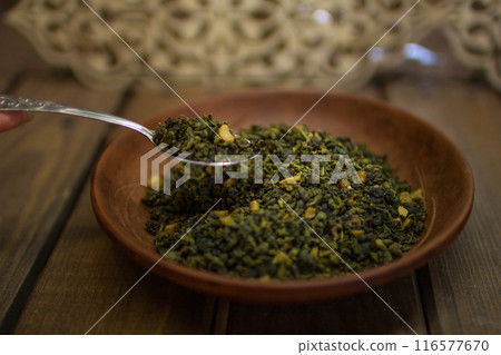 A clay plate with green fruit tea stands on a wooden table. 116577670