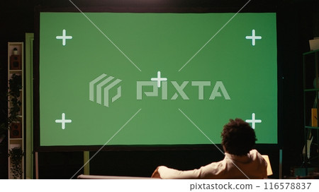 Man using green screen modern TV to watch news program broadcasting in living room. Person watching mockup ultrawide television display showing VOD channel, relaxing on couch 116578837