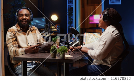 Man using high tech microphones to ensure optimum sound quality for audience listening at home while interviewing guest. Happy content creator using professional audio gear, presenting interviewee Man using high tech microphones to ensure optimum sound quality for audience listening at home while interviewing guest. Happy content creator using professional audio gear, presenting interviewee 116578853