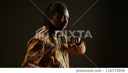 Cool person chatting on phone call using smartwatch, answering call and having remote conversation over black background. Trendy guy enjoys his modern wristwatch, telecommunications. 116578956