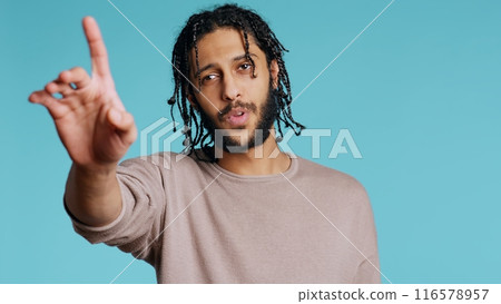 Assertive Middle Eastern man doing stop hand gestures. Annoyed BIPOC person doing firm halt sign gesturing, wishing to end concept, isolated over blue studio background, camera B 116578957