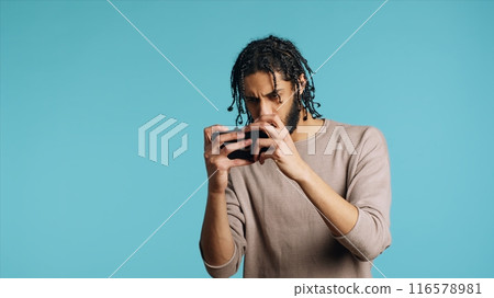 Upbeat man playing intense videogames on smartphone, celebrating victory, having fun. Joyous gamer enjoying game on phone, excited about win, isolated over studio background, camera A Upbeat man playing intense videogames on smartphone, celebrating victory, having fun. Joyous gamer enjoying game on phone, excited about win, isolated over studio background, camera A 116578981