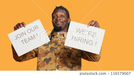 Job recruiter putting hiring messages and ads on papers to obtain new personnel for job vacancy at multinational company. African american employee managing recruitments and interviews. 116579007