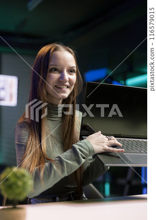 Happy teenager presenting laptop from brand sponsoring video, urging subscribers to purchase it. Joyful internet star does influencer marketing by advertising digital device to audience Happy teenager presenting laptop from brand sponsoring video, urging subscribers to purchase it. Joyful internet star does influencer marketing by advertising digital device to audience 116579015