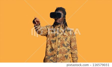 Cool guy using virtual reality glasses in studio, enjoying 3d vision and interactive simulation vr headset on camera. Modern person having fun with goggles, artificial intelligence concept. Cool guy using virtual reality glasses in studio, enjoying 3d vision and interactive simulation vr headset on camera. Modern person having fun with goggles, artificial intelligence concept. 116579031