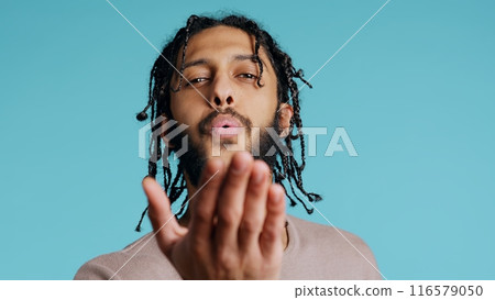 Middle Eastern frisky playful man blowing kisses to camera, being flirty. Lively charming BIPOC person having fun sending air kisses, doing romantic gesturing, studio background, camera B close up 116579050