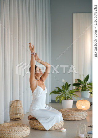Girl in white dress does aesthetic gymnastics in gym. Girl doing yoga in the gym 116579262