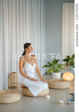 Girl in white dress does aesthetic gymnastics in gym. Girl doing yoga in the gym Girl in white dress does aesthetic gymnastics in gym. Girl doing yoga in the gym 116579269