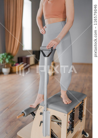 A detailed closeup of a foot work and core exercise on a Balanced Body Chair machine illuminated by sunlight 116579846
