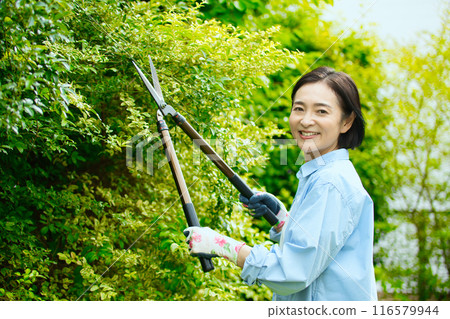 微笑的中年婦女照顧花園樹木 116579944
