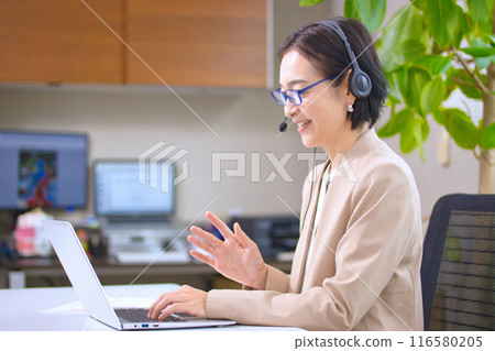 一位戴著耳機在辦公室工作的中年婦女 116580205