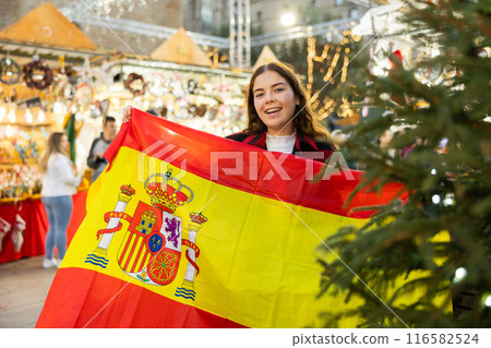 Cheerful girl with flag of Spain at Christmas city market Cheerful girl with flag of Spain at Christmas city market 116582524
