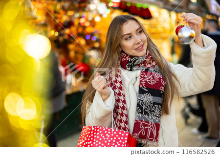 Portrait of girl with gift bag choosing Christmas tree balls Portrait of girl with gift bag choosing Christmas tree balls 116582526