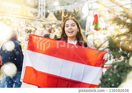 Happy girl with Austrian flag waving at New Year fair 116582636