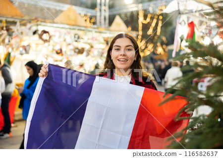 Smiling girl with flag of France walking on street Christmas fair 116582637