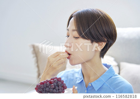 Woman eating grapes at home 116582818