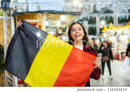 Smiling girl with flag of Belgium walking on street Christmas fair 116583619