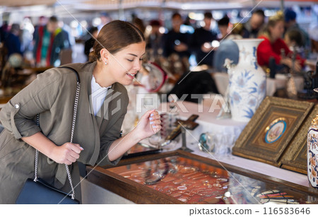 Young woman looking at vintage items at flea market Young woman looking at vintage items at flea market 116583646