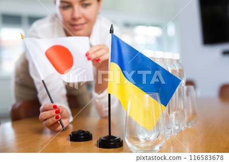 Unrecognizable girl sets midget flags of Ukraine and Japan before international negotiations Unrecognizable girl sets midget flags of Ukraine and Japan before international negotiations 116583678