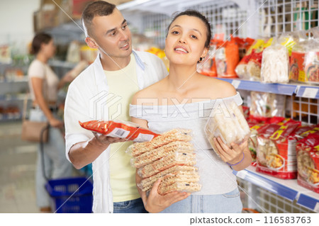 Cheerful interracial couple choosing Asian noodles at food store 116583763