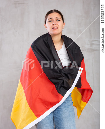 Sad young female student with flag of Germany against of gray wall background 116583765