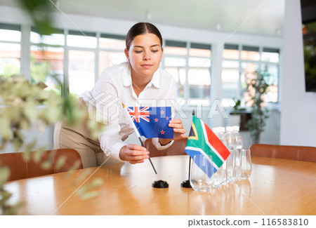 Positive young woman putting little flag of Australia on table next to the flag of South Africa Positive young woman putting little flag of Australia on table next to the flag of South Africa 116583810