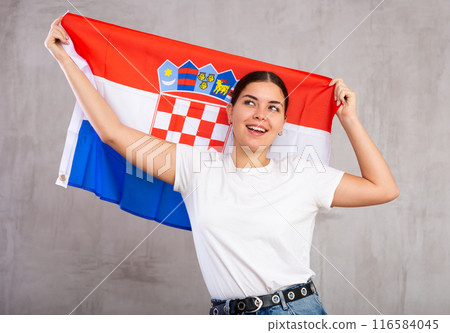 Joyful young woman waving state flag of Croatia against gray wall background Joyful young woman waving state flag of Croatia against gray wall background 116584045