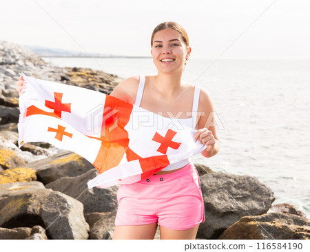 Young woman on coast posing with flag of Georgia 116584190
