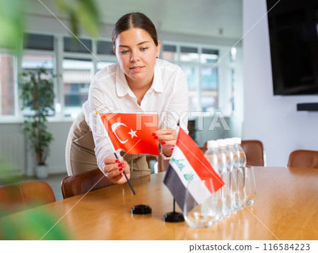 Female employee of the delegation sets flags of countries of Turkey and Iraq on the table before start of negotiations 116584223