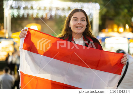 Happy girl with Austrian flag waving at New Year fair 116584224